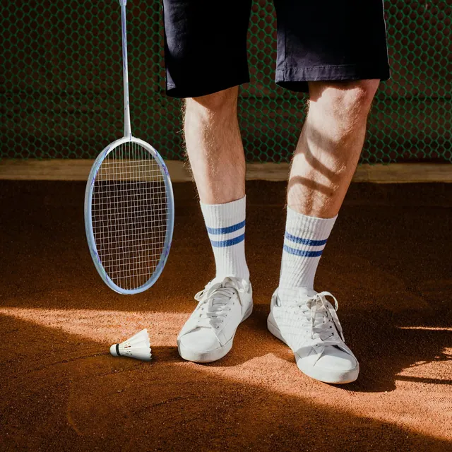 A player's feet, racket and shuttlecock on a clay court floor