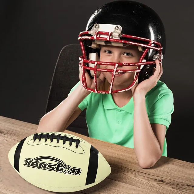 A child in a football helmet sitting at a table with a cream football